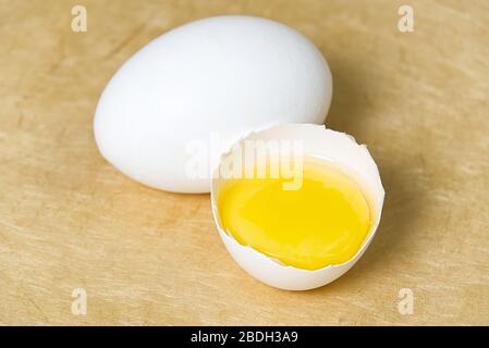 chicken white eggs with half broken egg on beige textured background Stock Photo