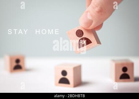 The concept of staying at home - abstract figures of people and a hand holding a patient with a virus COVID-19. Close up. Stock Photo