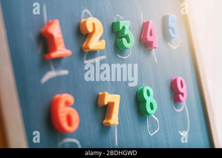 Learning numbers on a blackboard with colorful magnets and handwriting on blackboard during homeschooling at quarantine Stock Photo