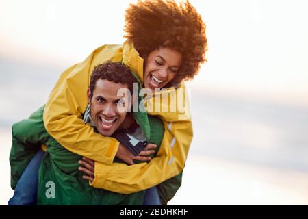 Mid adult man giving his girlfriend piggyback ride. Stock Photo