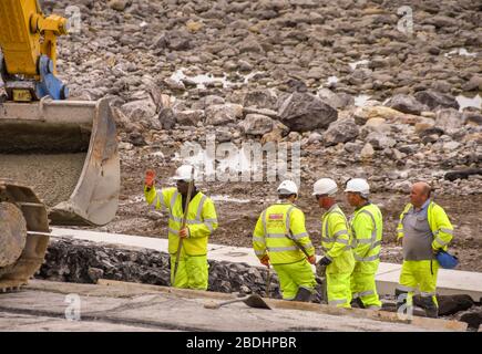 PORTHCAWL, WALES - JUNE 2018: Construction workers laying concrete on rocks on the seafront in Porthcawl to improve its appearance Stock Photo