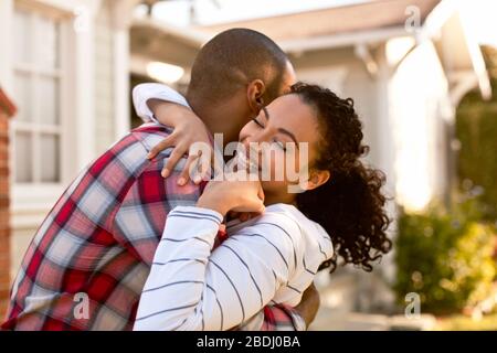 Mid-adult couple hugging in front of their new home. Stock Photo