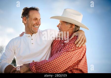 Two mature men embracing and smiling. Stock Photo
