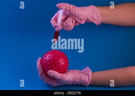 coronavirus vaccine. Syringe with a needle with a vaccine in hands in pink gloves from coronavirus on a blue background Stock Photo