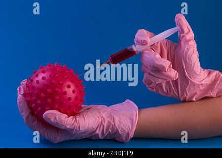 coronavirus vaccine. Syringe with a needle with a vaccine in hands in pink gloves from coronavirus on a blue background Stock Photo