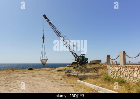 Crane for lifting fishing gear on a high steep sea shore. Fishing camp on Cape Atlesh. Tarkhankut Peninsula, Crimea Stock Photo