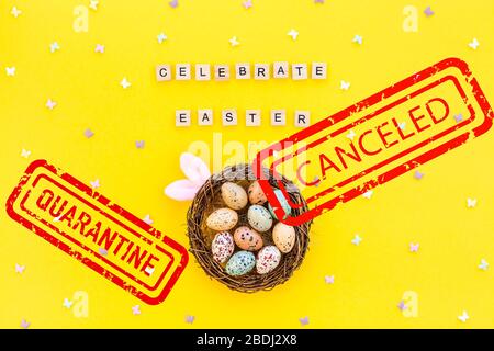 Pandemic lockdown Easter day concept. Flat lay top view creative holiday composition Easter eggs bunny ears spring on yellow background with red Cance Stock Photo
