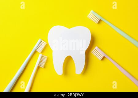 Toothbrushes and tooth on yellow background, top view Stock Photo