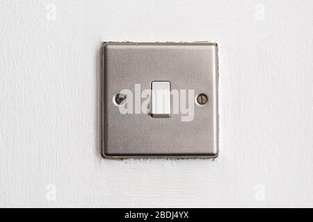 Brushed metal light switch on white wall inside a house Stock Photo