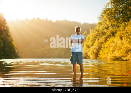 Portrait of a smiling senior man standing in a lake while on vacation Stock Photo