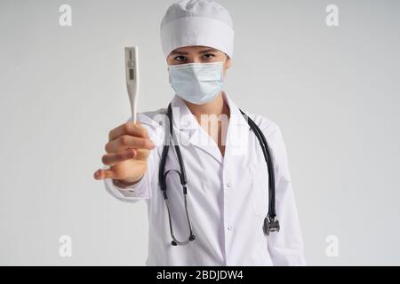 Young female doctor showing thermometer over white background, studio shot Stock Photo