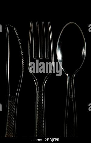 Close up of Transparent plastic Knife fork and spoon on a black background Stock Photo