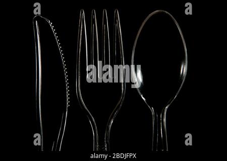 Close up of Transparent plastic Knife fork and spoon on a black background Stock Photo