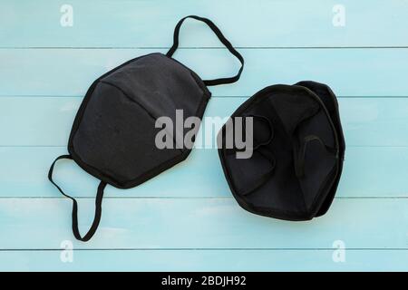Black cotton mouth and nose mask to protect against flu and virus. Face mask during the coronavirus pandemic. Black face masks on a blue wooden backgr Stock Photo