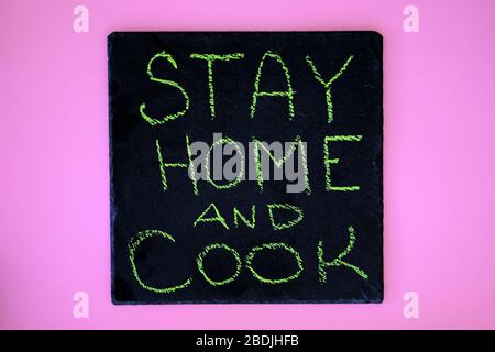 Inscription in chalk on a black chalkboard stay home and cook. The concept of preparing food, hobbies, activities during quarantine all over the world Stock Photo