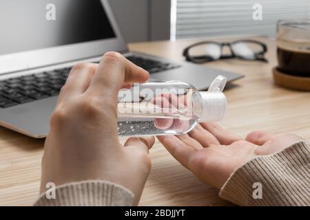 Closeup womans hand uses antibacterial gel to prevent coronavirus on her workplace. Hand sanitizer alcohol gel is pouring from a bottle on a Stock Photo