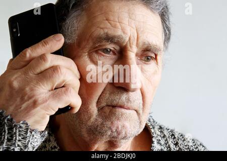 Portrait of unshaven elderly man talking on mobile phone, smartphone in male hands close up. Concept of communication in retirement Stock Photo