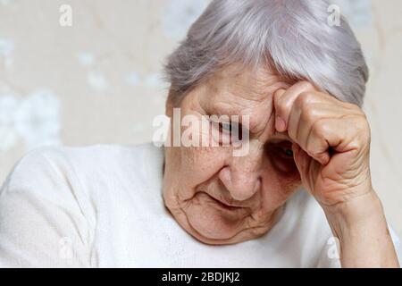 Elderly woman thought about something. Sad female with gray hair and wrinkled skin, concept of headache, memories, loneliness and old age Stock Photo