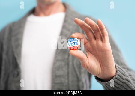 Law abiding american citizen holding vote pin in hand Stock Photo