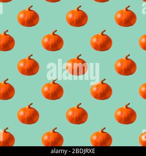 Flat lay Seamless Pattern made with orange pumpkin over neo mint background. Stock Photo