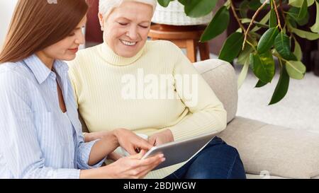 Daughter teaching mother using digital tablet at home Stock Photo