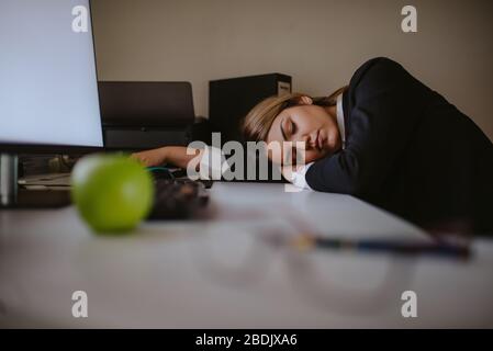 Tired young blond caucasian businesswoman sleeping in office Stock Photo