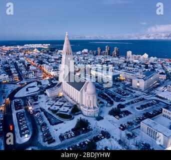 Drone view of Hallgrimskirkja church with tall tower in snow covered city at dusk time in Reykjavik Stock Photo