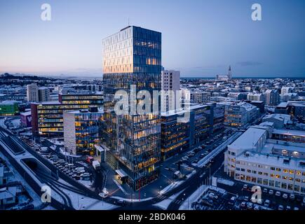 From above of snowy streets of contemporary city district with illuminated high buildings and empty road in winter morning in Iceland Stock Photo