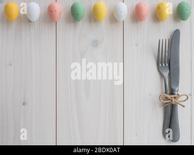 easter eggs and vintage cutlery on wooden board. table set. top view Stock Photo