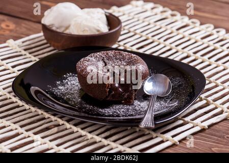 Concept: restaurant menus, healthy eating, homemade, gourmands, gluttony. White plate with chocolate fondant and ice cream on a messy vintage wooden b Stock Photo