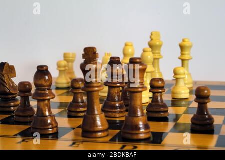 Chess pieces stand on a wooden board close-up isolated on a white background. Stock Photo