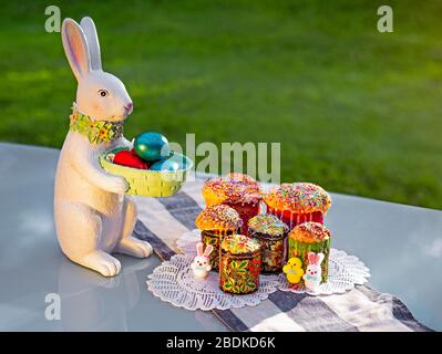 A rabbit souvenir with painted eggs and traditional Easter bread on the tamle with green grass on background. Stock Photo