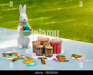 A rabbit souvenir with painted eggs and traditional Easter bread on the tamle with green grass on background. Stock Photo