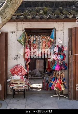 Suzhou China - May 3, 2010: Closeup of doorway into small shop selling colorful shawls, purses, and bags in Chinese style. Stock Photo