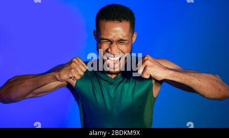 Sporty Man Shouting Emotionally Clenching Fists In Studio, Panorama Stock Photo