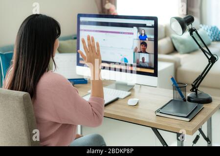 Asian business woman say hello or goodbye to her colleagues about plan in video conference. Multiethnic business team using computer for a online meet Stock Photo