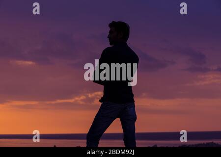businessman standing in front of the sea at sunset, side profile view of man standing thinking about future outdoors background Stock Photo
