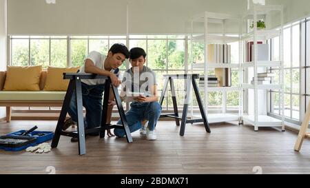 Two carpenters discussed the type of bench being assembled. Handyman installing wooden bench in new house. House renovation service. Morning work atmo Stock Photo