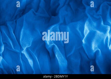 Texture of classic blue Wrinkled Fabric. Trendy color of clothes. Close-up. Stock Photo