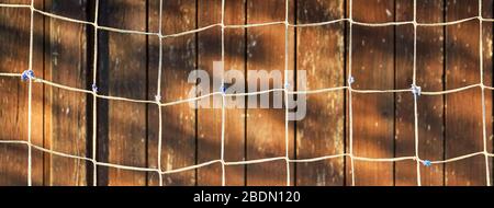 A net against a wooden background as a panorama. Stock Photo
