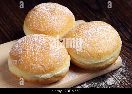 Three sugary donuts on a wooden board Stock Photo