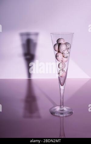 Quail eggs in champagne flute on glossy background. Creative still life. Easter concept. Stock Photo