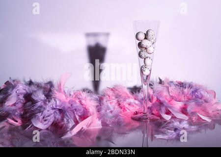 Quail eggs in champagne flute with feathers on glossy background. Creative still life. Easter concept. Stock Photo