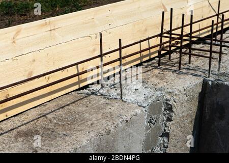 Formwork for the foundation of the house. Closeup of house foundation made from concrete shuttering blocks filled with mortar and reinforcement bars. Stock Photo