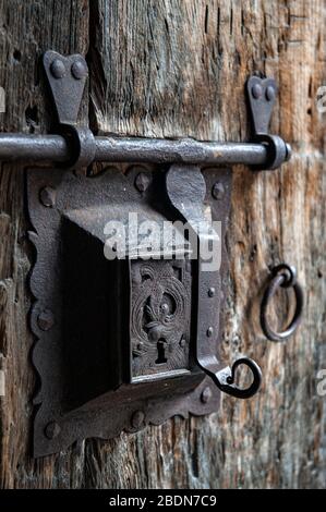 Ancient rusty steel lock bolt with a key hole installed on an old wooden door from medieval age Stock Photo