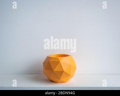Cactus pot. Concrete pot. Empty orange modern geometric concrete planter on white wooden shelf isolated on white background. Stock Photo