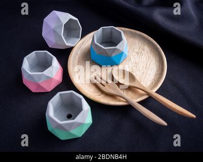 Cactus pot. Concrete pot. Beautiful empty small modern geometric concrete planters with painted on wooden plate on black fabric background. Stock Photo