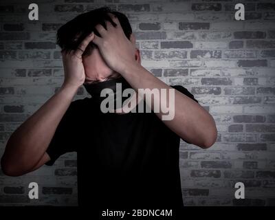 Asian panic and serious man wearing black protective face mask and black shirt on dark background, Coronavirus and pm 2.5 concept. Stock Photo