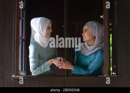 Asian Malay Muslim girls greetings during Hari Raya Aidilfitri. Malaysian people living lifestyle. Stock Photo