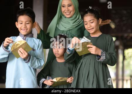 Muslim family, children received money packet as blessing, Hari Raya Eid Al-Fitr concept. Stock Photo